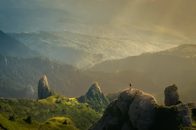 person stood on top of mountain surrounded by nature